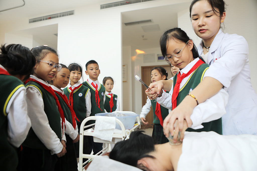 2023 年 10 月 18 日，学生们在中国西南部重庆市的一家医院参加拔罐疗法演示。/CFP